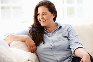 A smiling woman relaxing on a couch.
