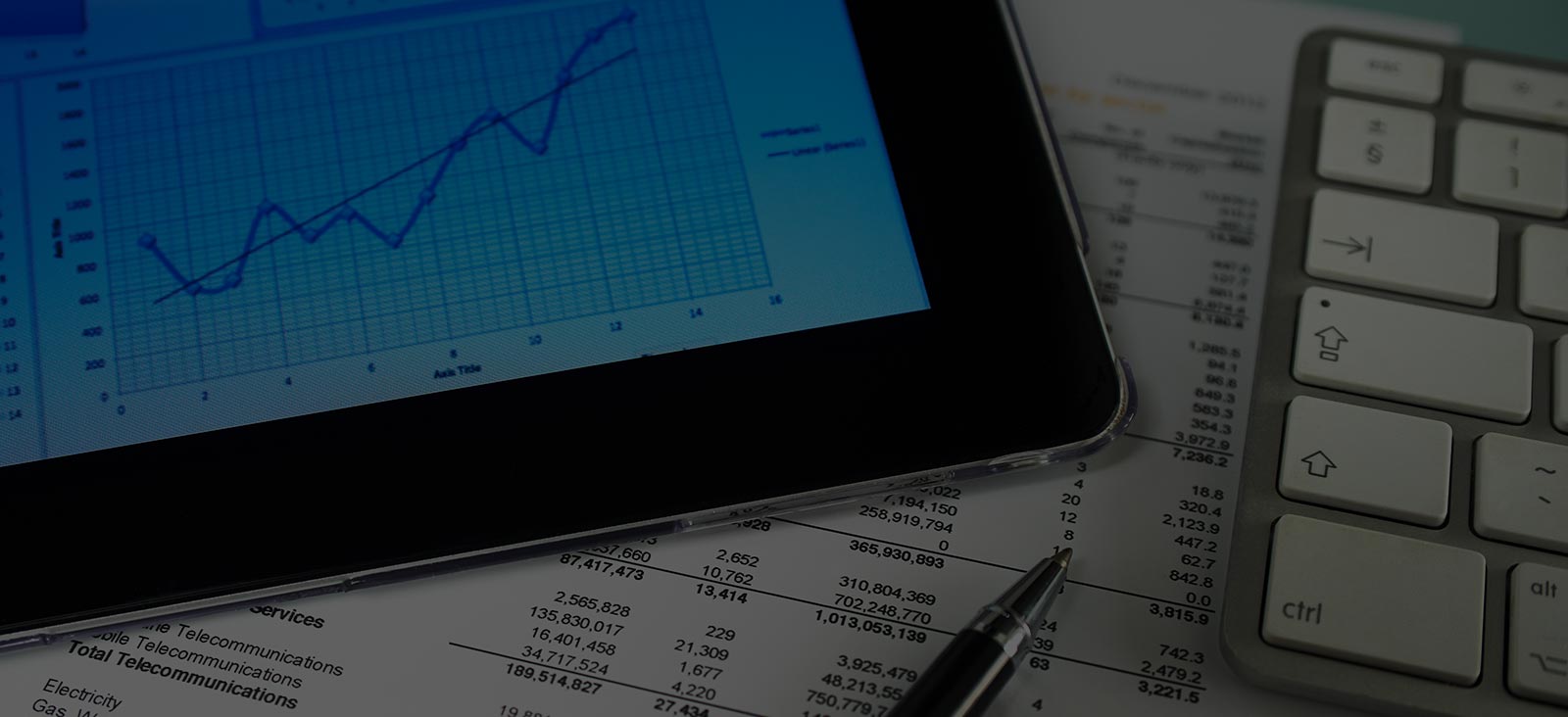 Close-up of a tablet displaying a financial graph, alongside documents and a keyboard