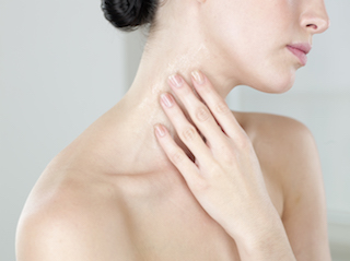 A close-up image of a woman's neck and shoulder, with her hand gently touching her neck.