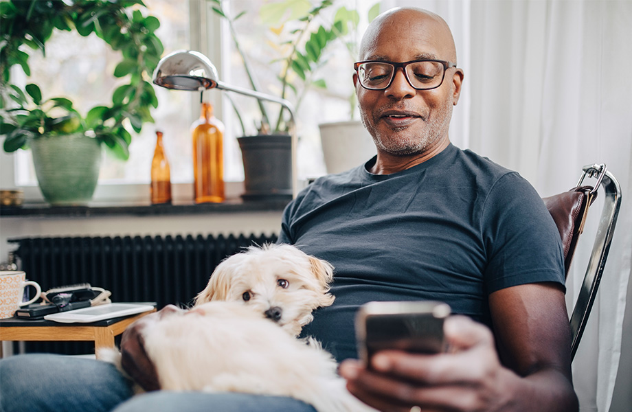 Man sitting with a dog and looking at his phone.