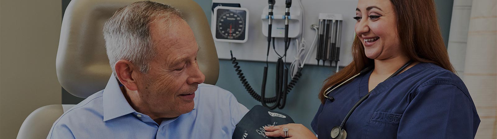 caregiving putting a blood pressure cuff on a patient