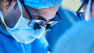 A neurosurgeon focuses on a procedure under magnifying glasses.
