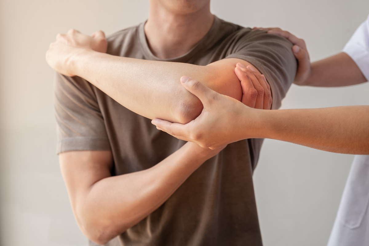 A physical therapist assists a patient with stretching exercises for their elbow