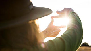 A person frames the sun with their hands.