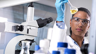 A scientist examining a liquid sample in a lab.