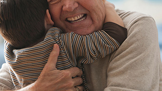 An older man hugs a young child warmly.