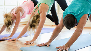 Three people practicing yoga in downward dog pose.