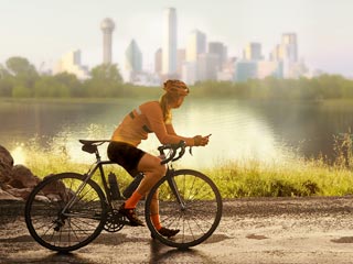 cyclist resting by a lake with a city skyline backdrop