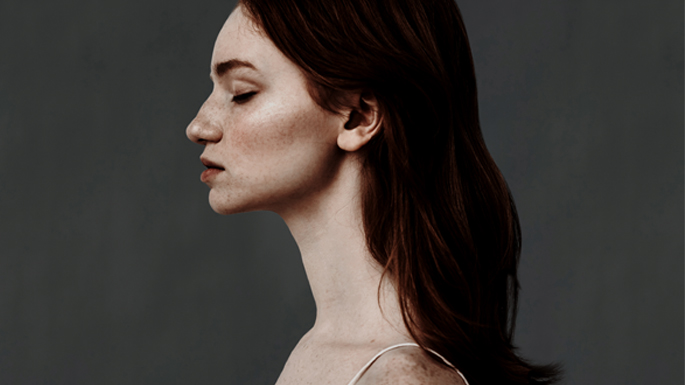 Side profile of a young woman with closed eyes, deep in thought or distressed.