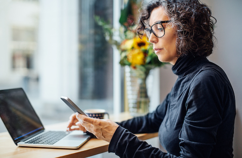 Woman using a smartphone and laptop at a desk