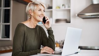 Woman speaking on the phone while using a laptop